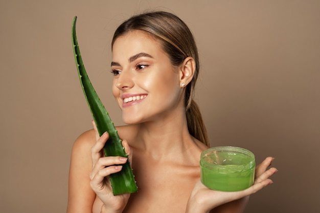 1649487581 smiling happy young female model holding aloe leaf jar aloe gel beige background concept skin care moisturizing with natural cosmetics 121946 2683
