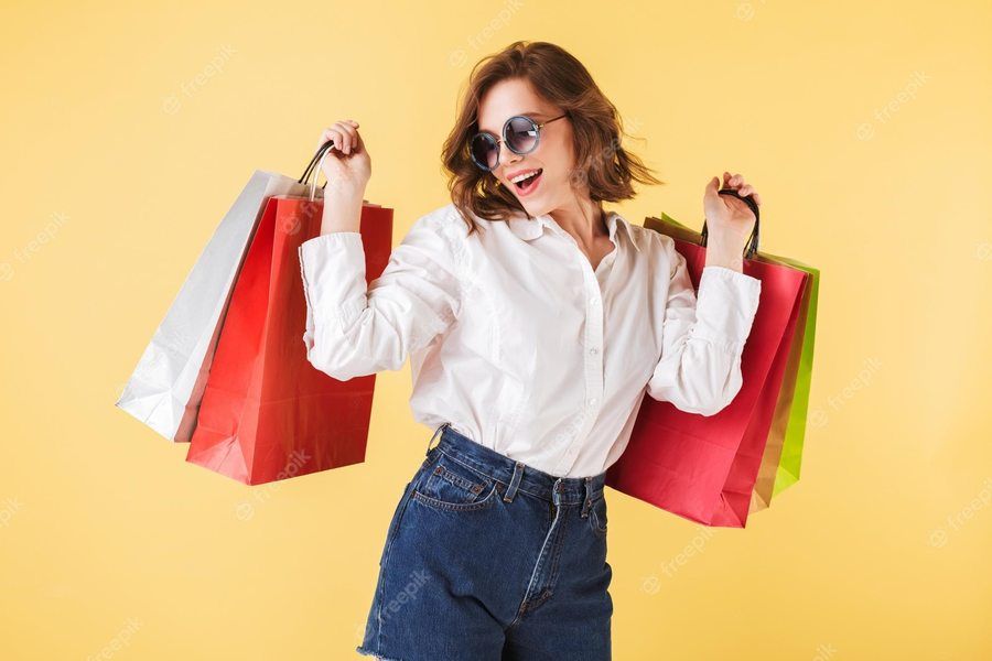 1684779396 portrait happy lady sunglasses standing with colorful shopping bags hands pink background young woman standing white shirt denim shorts 574295 1182
