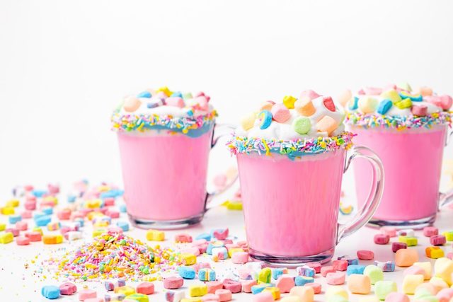 1549008168 5d4b3103 unicorn hot chocolate pink hot chocolate with whipping cream lucky charms marshmellows on a white table  1200x800