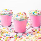 Icon 5d4b3097 unicorn hot chocolate pink hot chocolate with whipping cream lucky charms marshmellows on a white table 1400x933